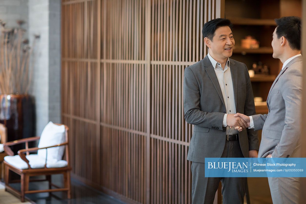 Cheerful Chinese businessmen shaking hands