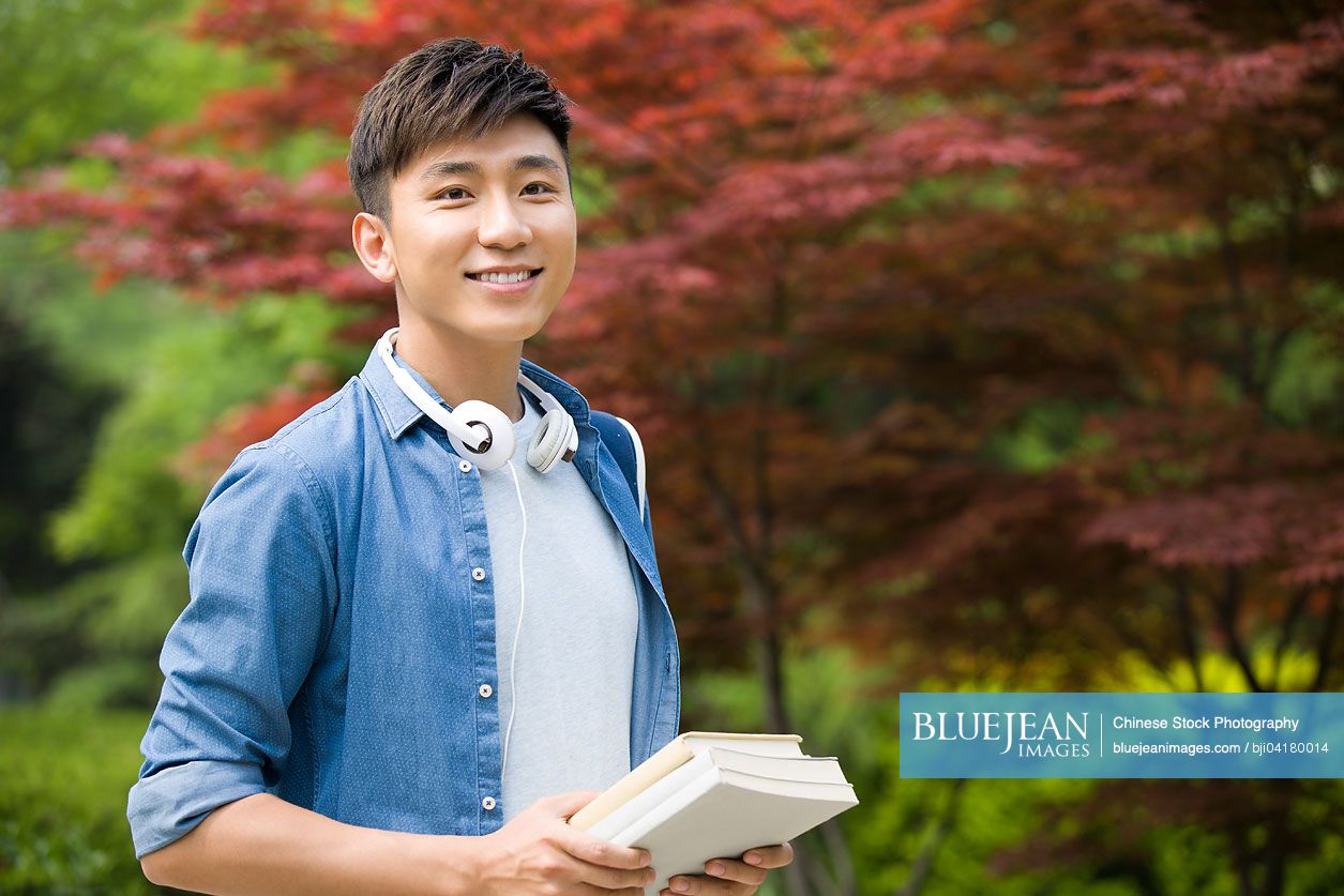 Happy male Chinese college students with books