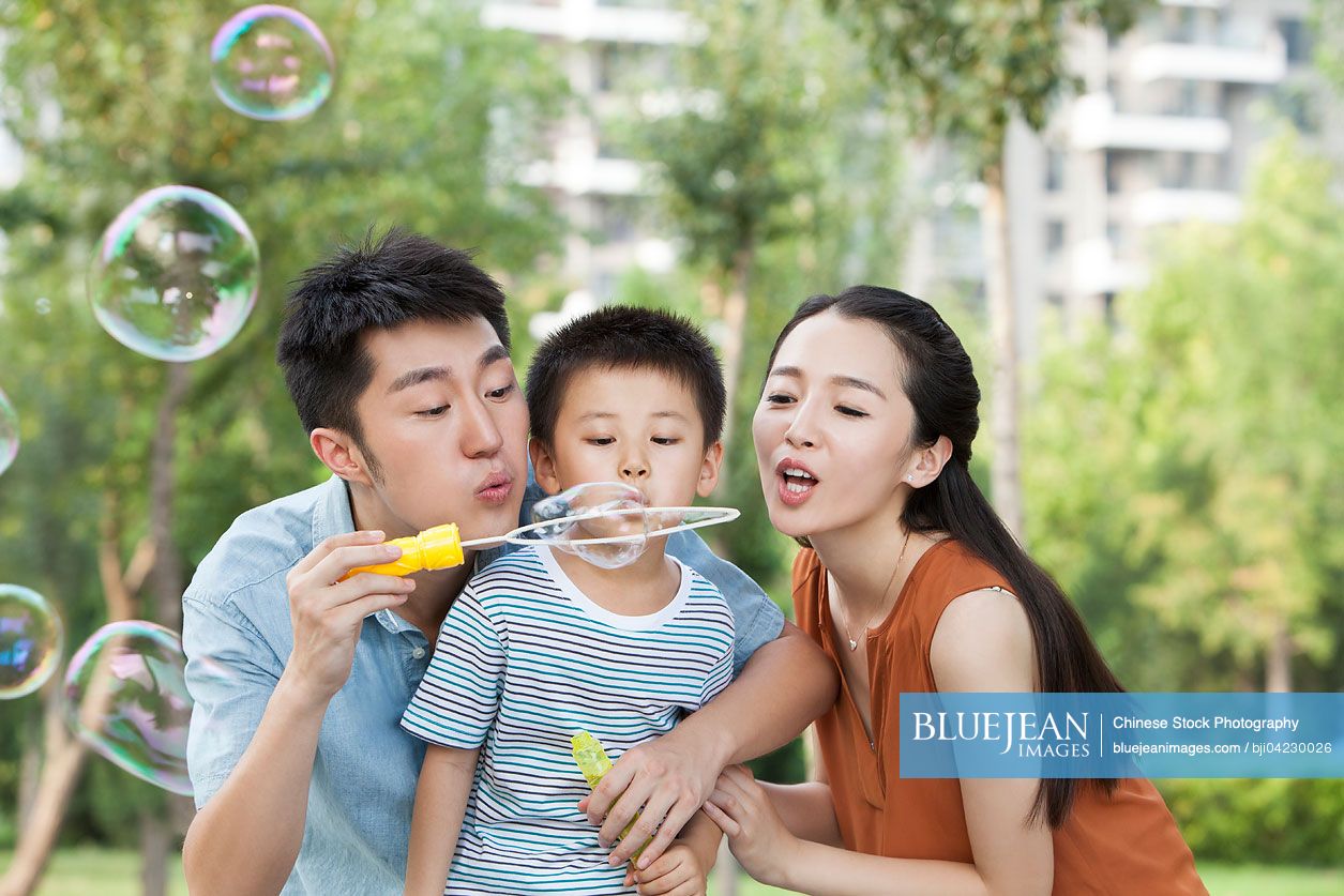 Happy young Chinese family blowing bubbles