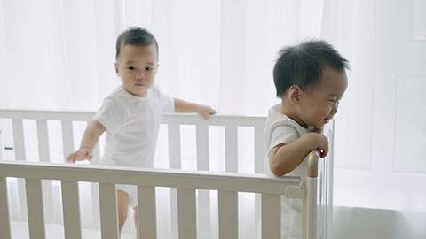 Two twin babies playing in their crib