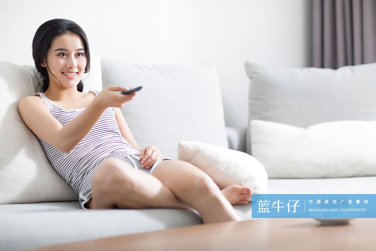 年轻女子在沙发上看电视