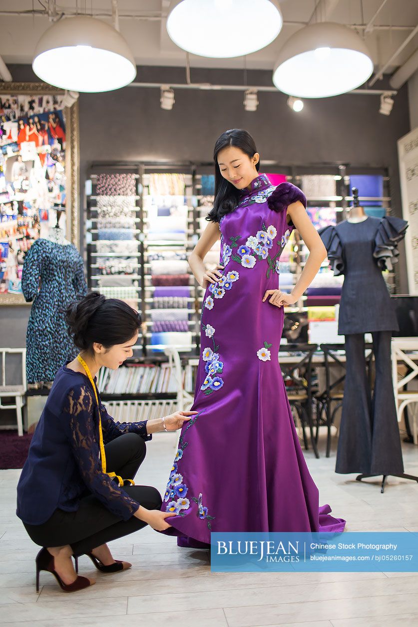 Chinese fashion designer adjusting customer's dress