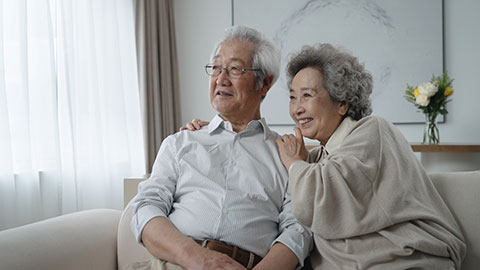 Cheerful senior Chinese couple sitting on sofa,4K