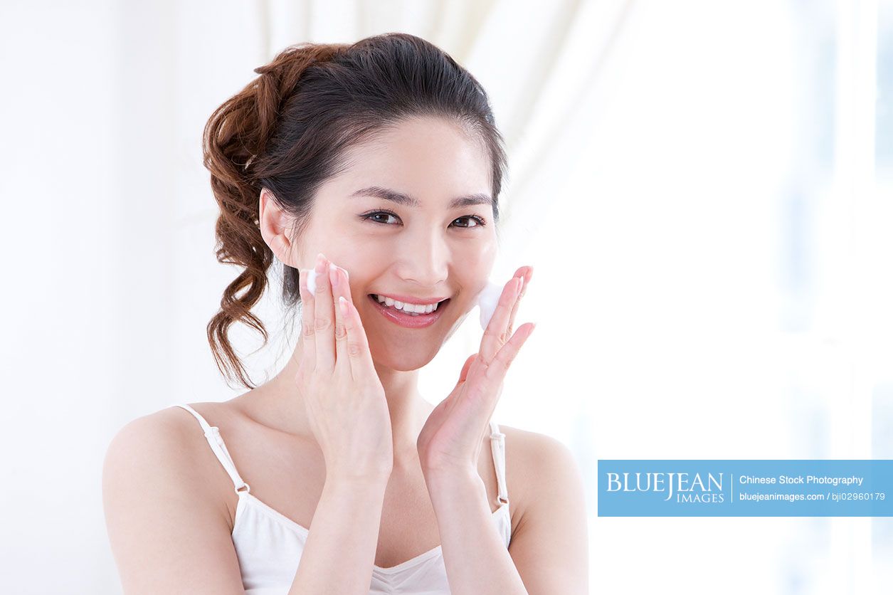 Young Chinese woman using facial cleanser to wash face