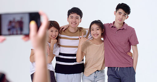 Cheerful young Chinese friends taking photos with smartphone,4K