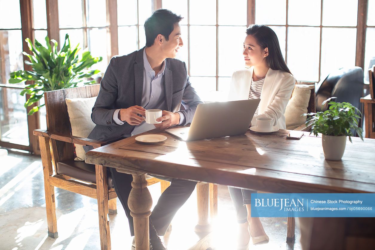 Young Chinese business people talking in coffee shop