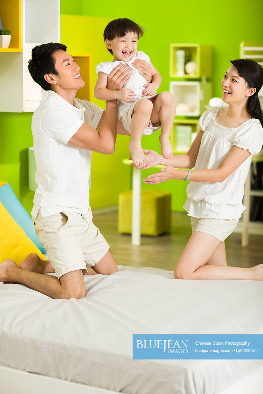 Happy Chinese family playing in bedroom