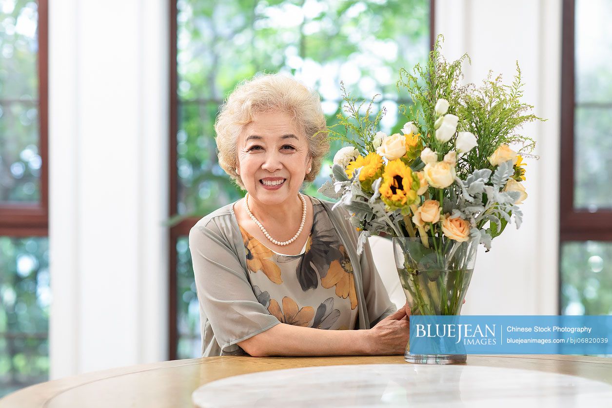 happy-senior-chinese-woman-arranging-flowers-at-home-high-res-stock