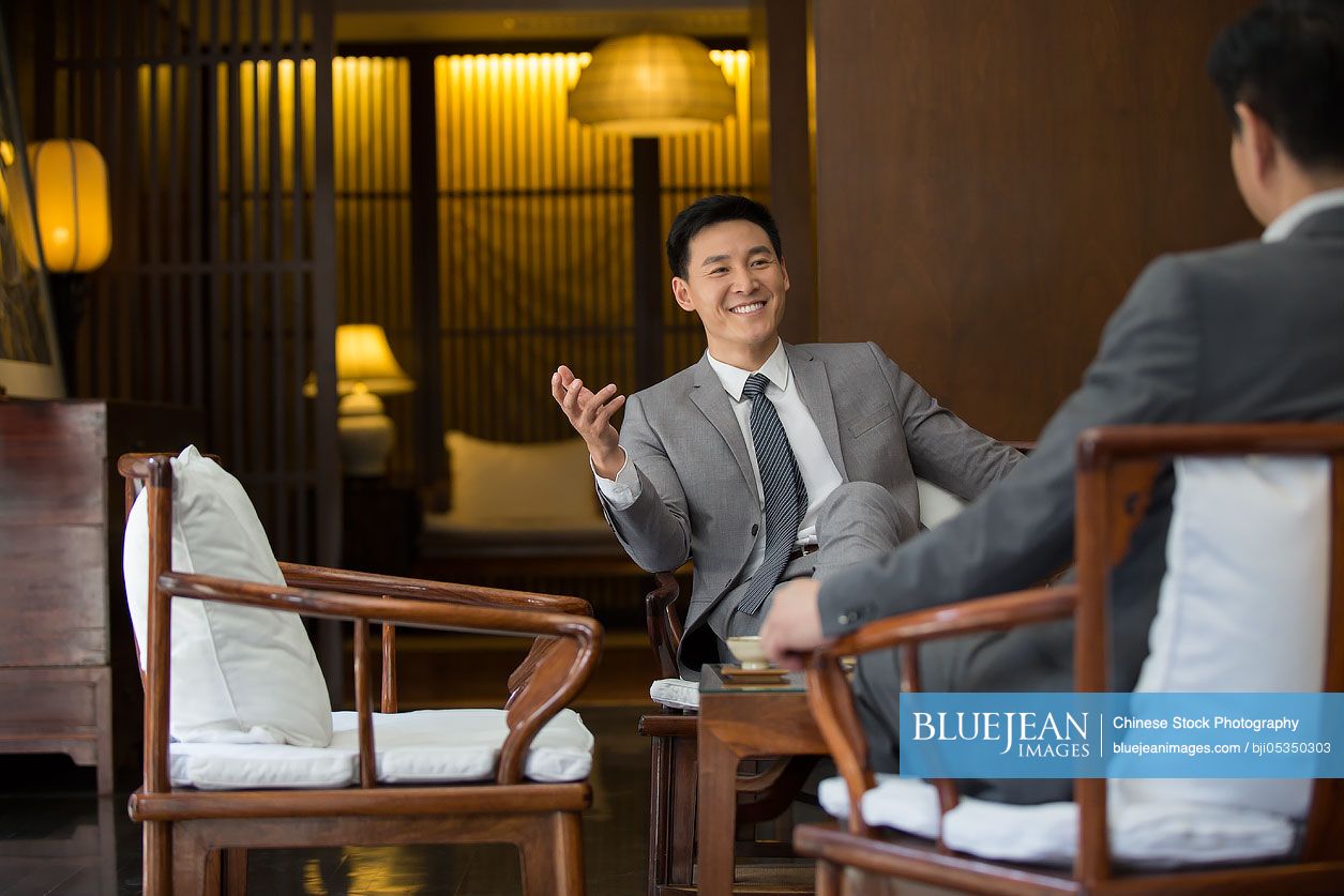 Cheerful Chinese businessmen talking in tea room