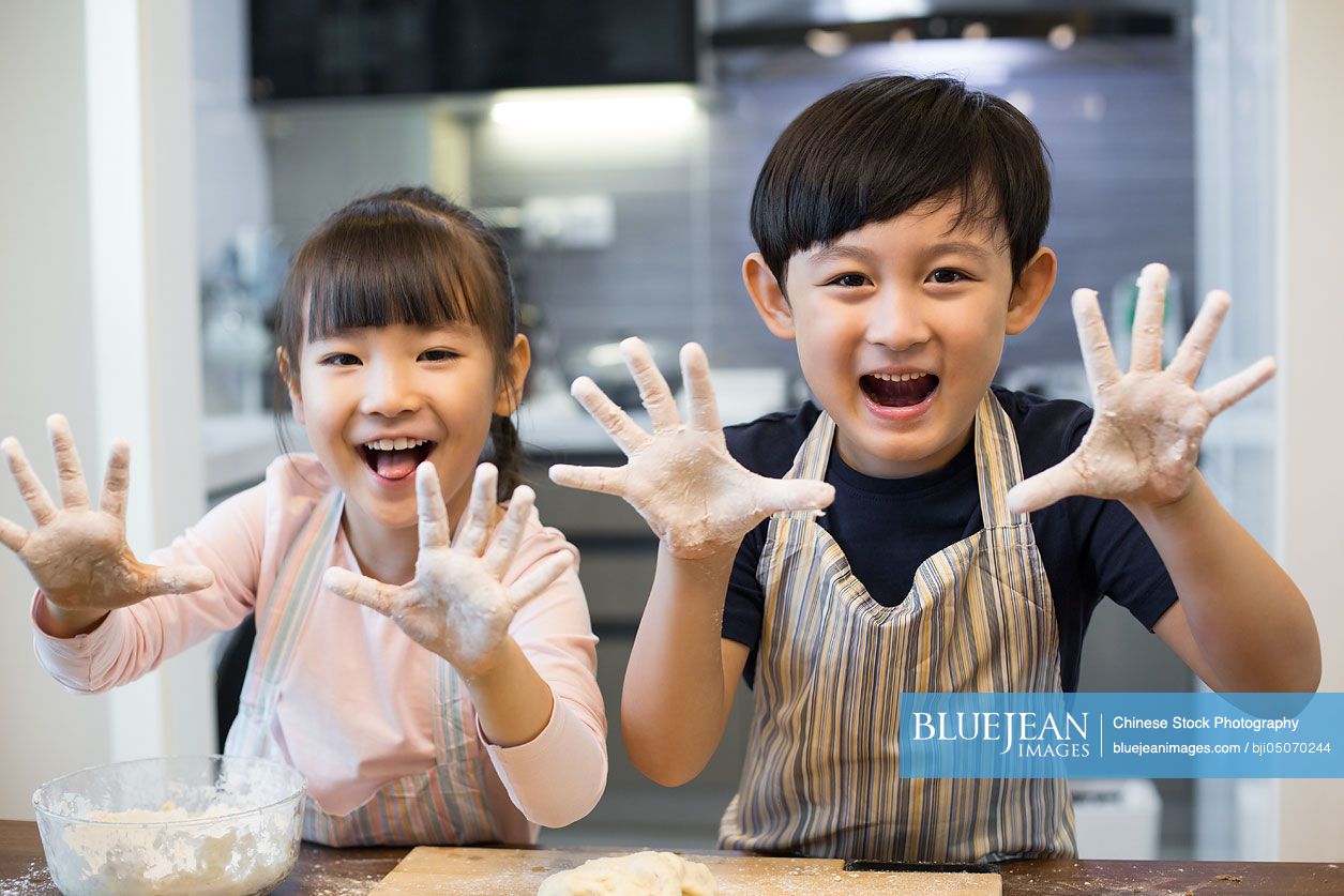 Happy Chinese siblings playing with flour