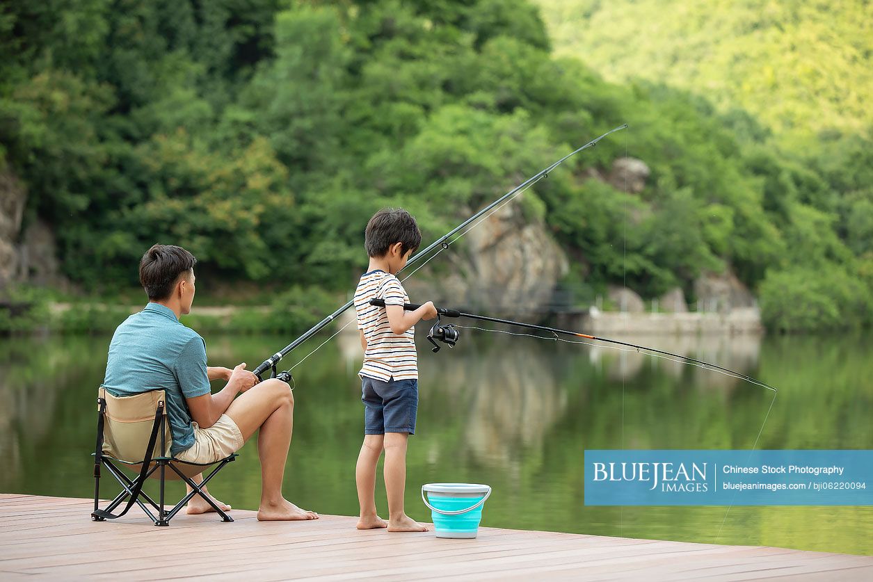 Chinese father and son fishing by the river