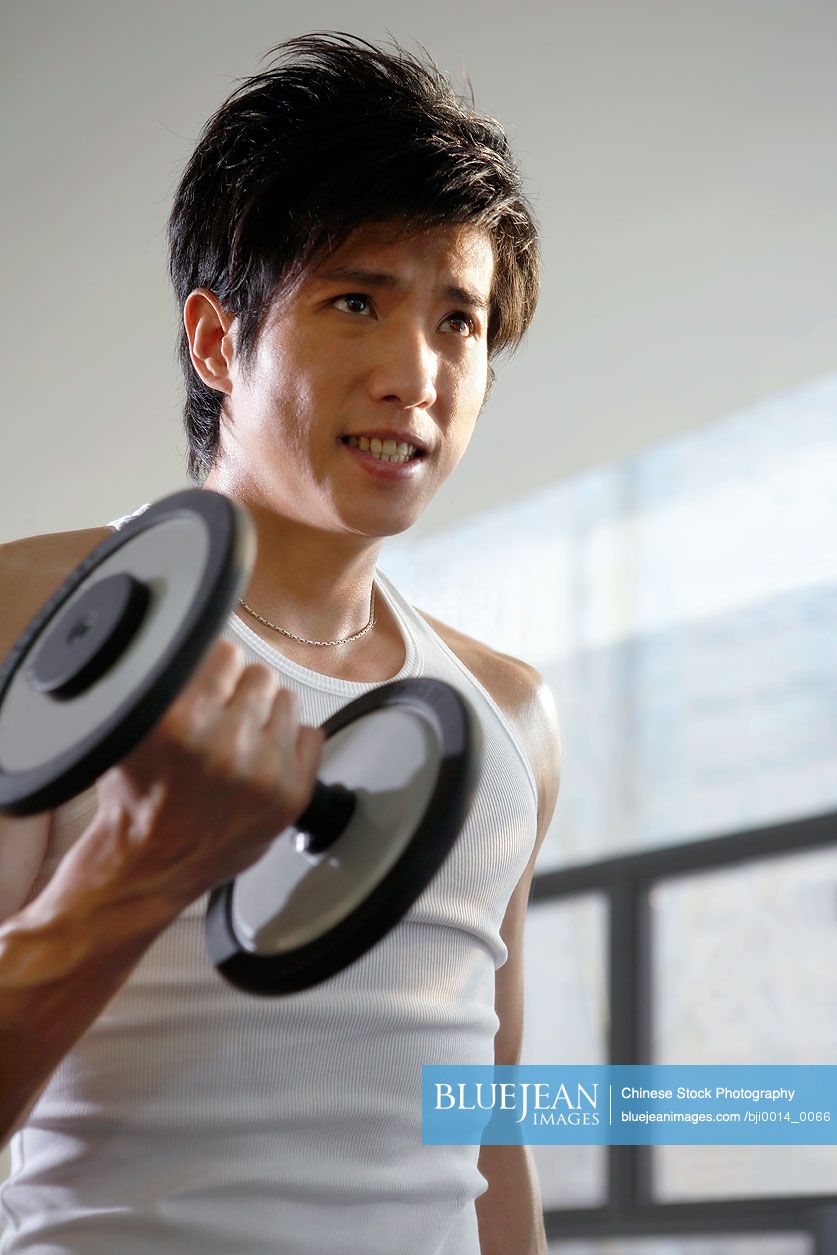 Chinese man lifting weights in gym