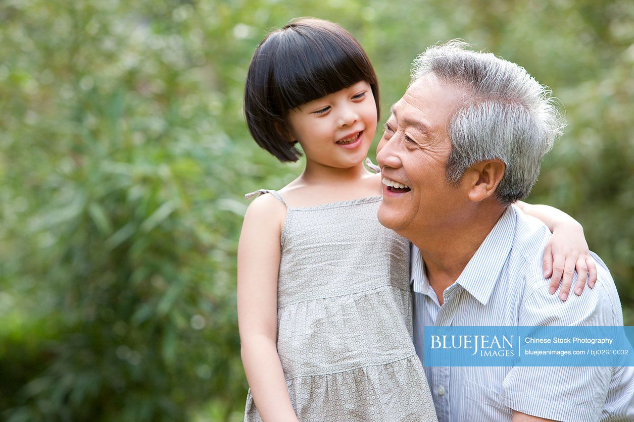 Chinese grandpa and grandaughter having fun in garden