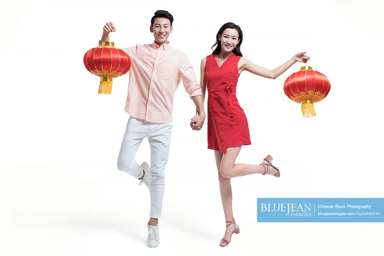 Cheerful young couple celebrating Chinese new year with traditional lanterns