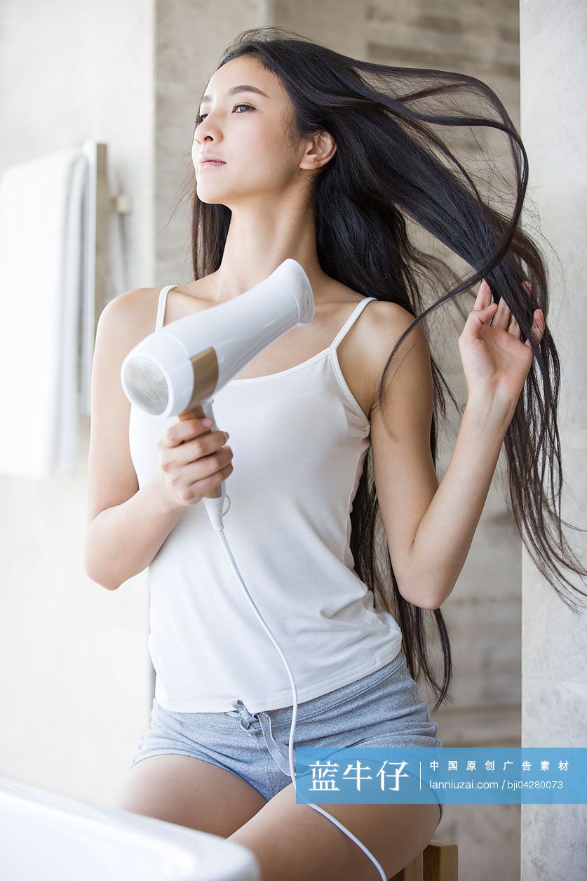 年轻女子用吹风机吹头发