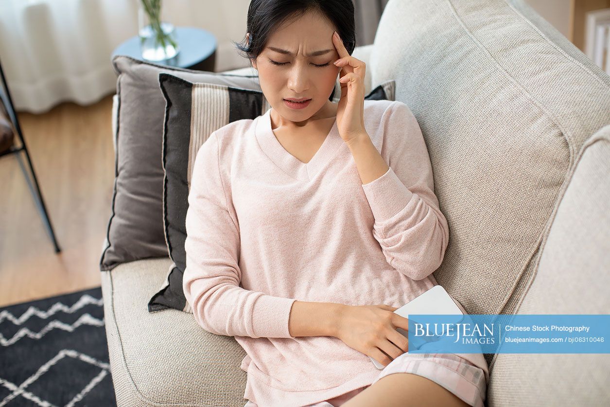 Young Chinese woman having a headache at home