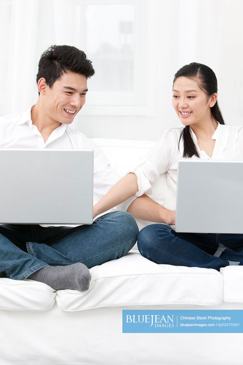 Happy young Chinese couple using laptop together