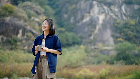 Cheerful young Chinese woman enjoying the beautiful natural scenery