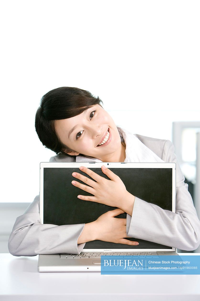 Chinese office worker hugging her computer