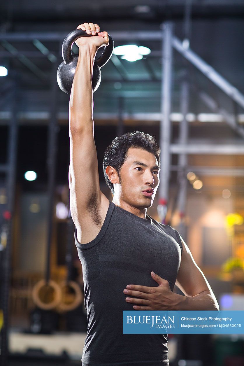 Young Chinese man training with kettlebell in crossfit gym