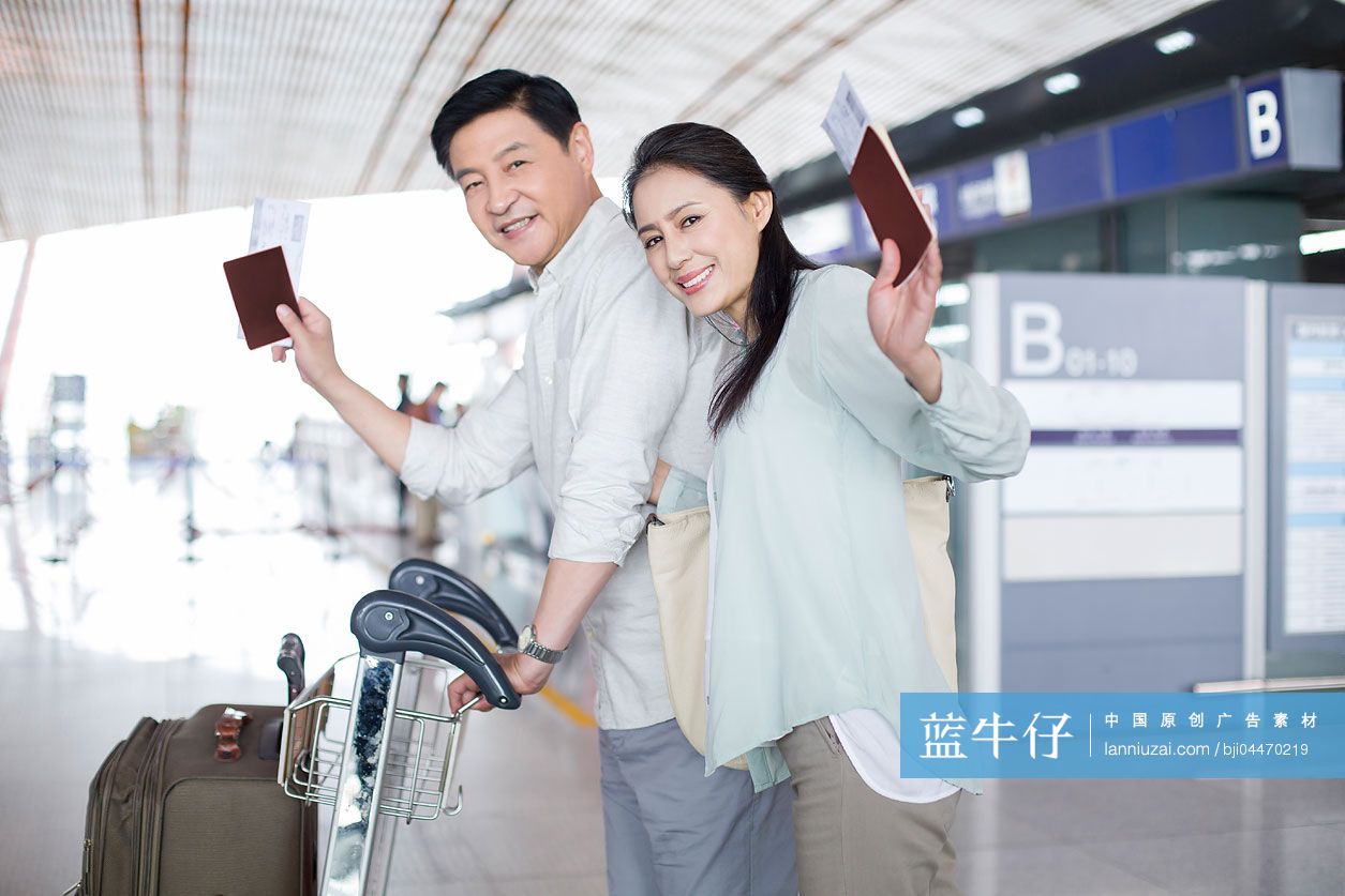 成熟中年夫妇推着行李箱在机场走