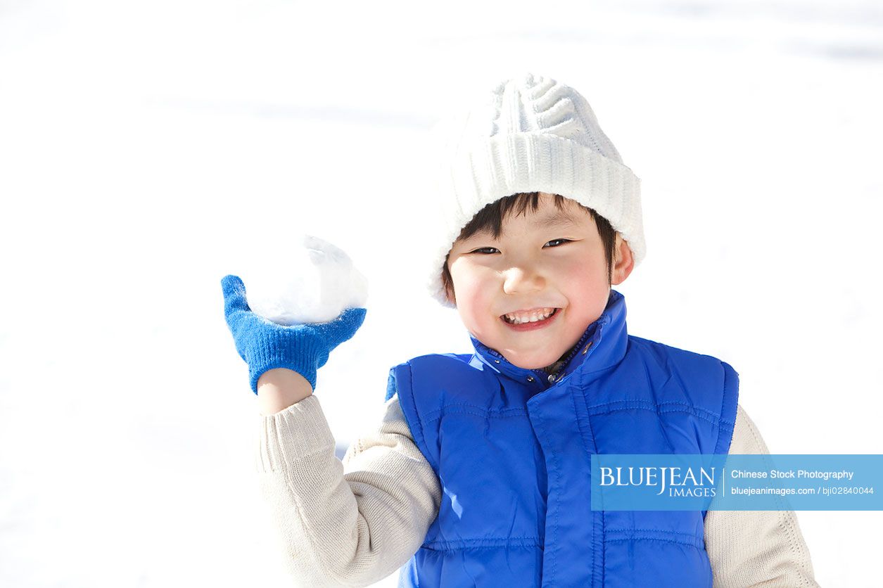 Little Chinese boy having fun in snow