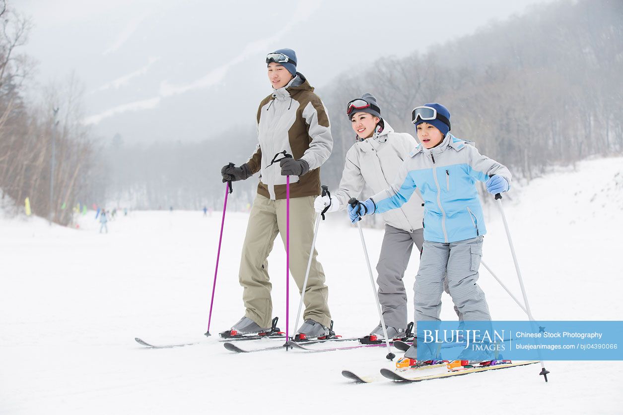 Young Chinese family skiing in ski resort