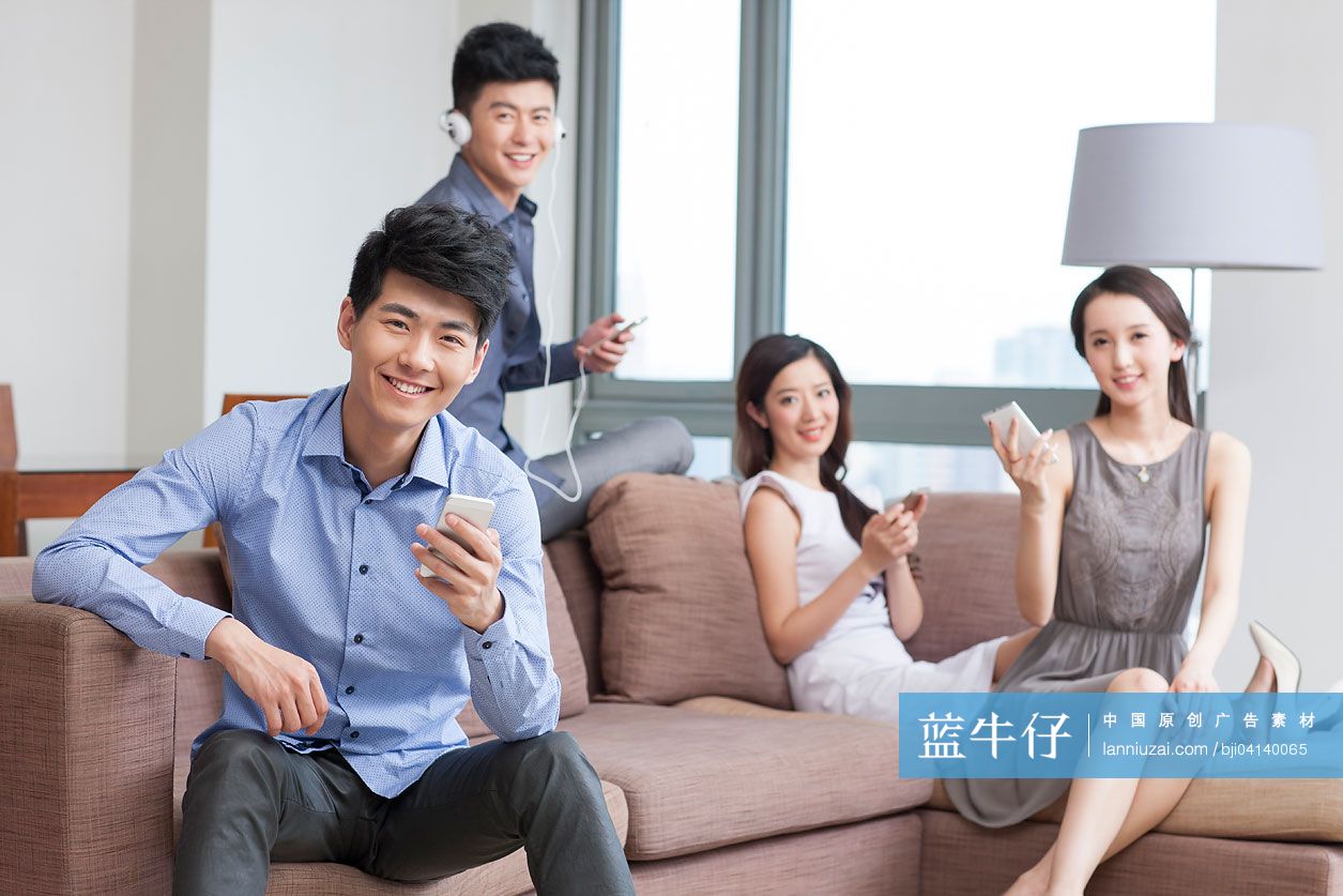 四个年轻人坐在沙发上使用手机