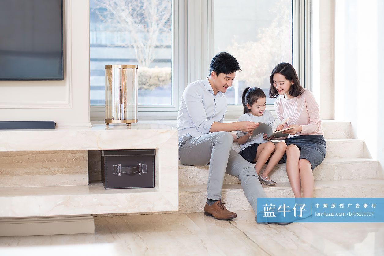 快乐的年轻家庭在客厅看书