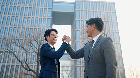 Confident Chinese business people holding hands outdoors