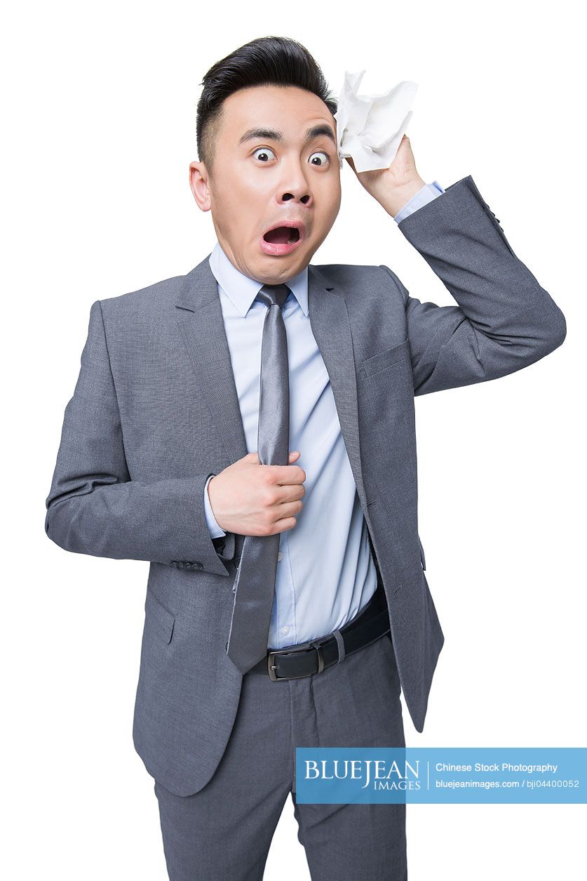 Young Chinese businessman wiping sweat with terrified expression