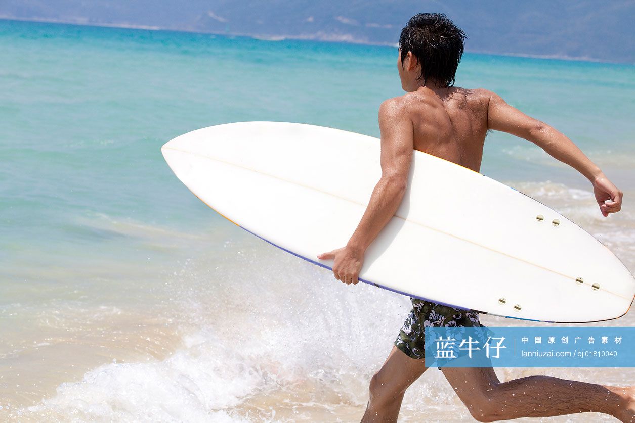 拿着冲浪板往海里奔跑的男孩