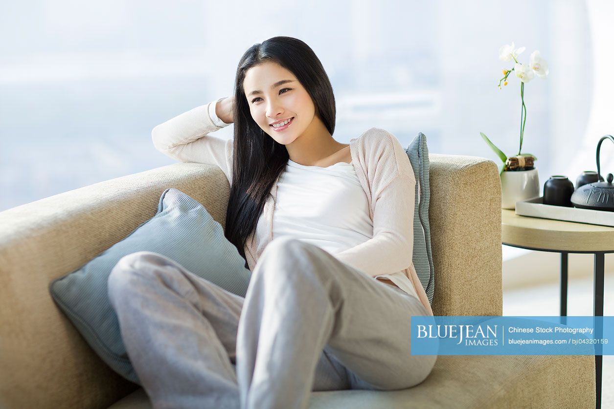 Happy young Chinese woman sitting by window