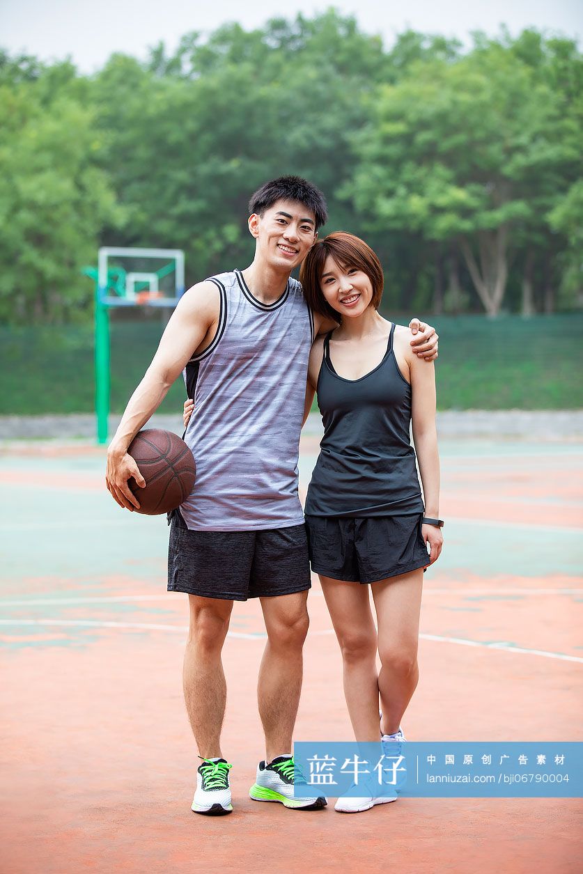 开心的年轻情侣在篮球场打篮球