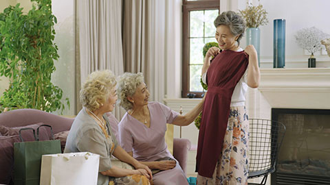 Happy senior Chinese woman showing her new dress to friends,4K