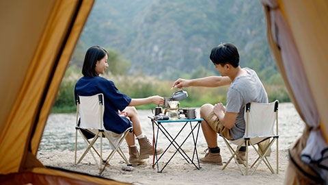 Happy young Chinese couple camping outdoors