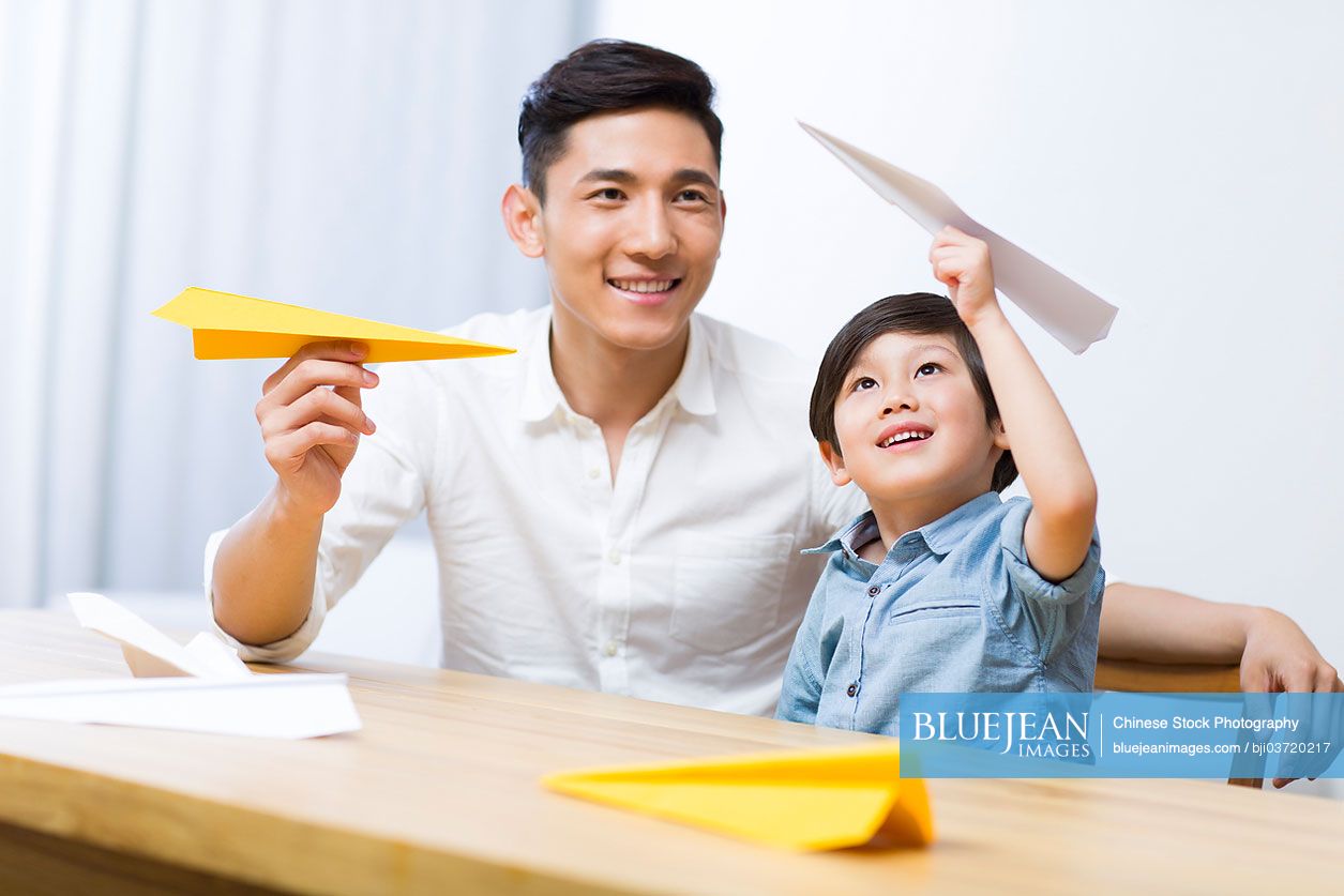 Chinese father an son making paper plane