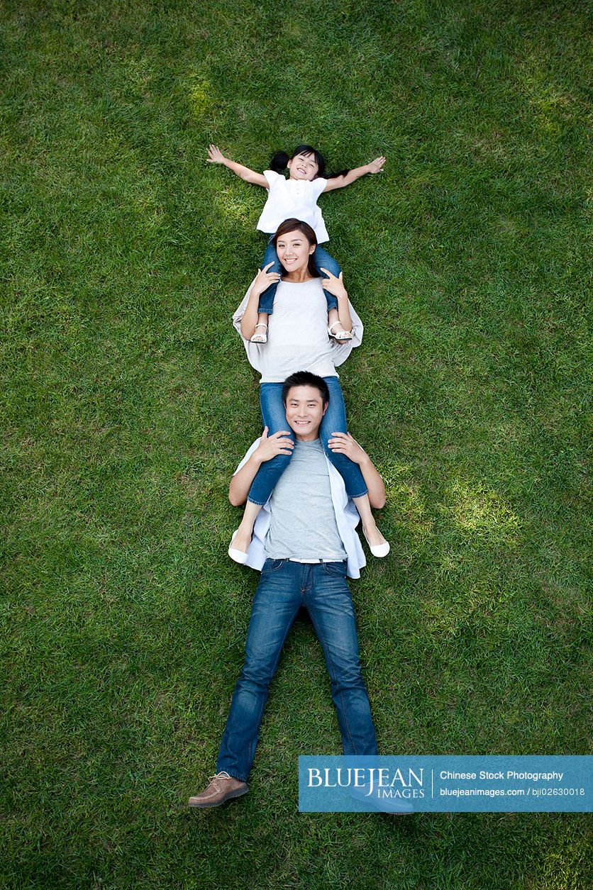 Young Chinese family lying down and playing on the grass