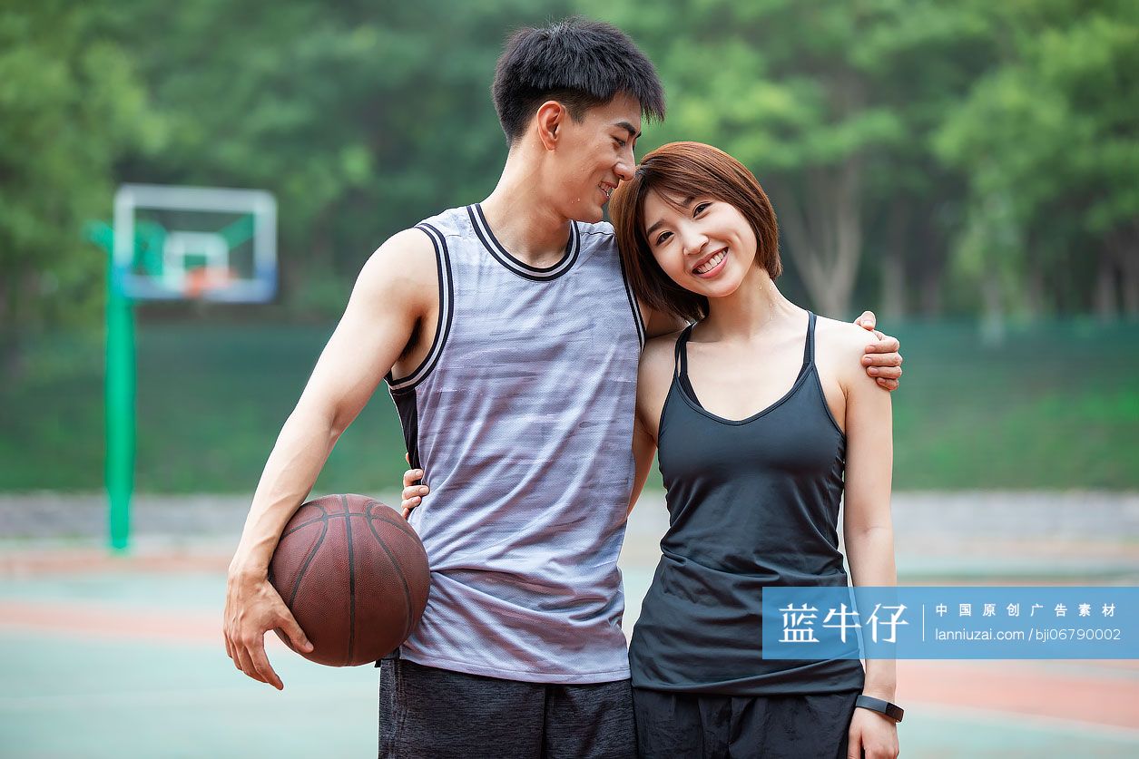 开心的年轻情侣在篮球场打篮球