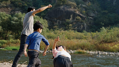 Happy young Chinese family camping outdoors