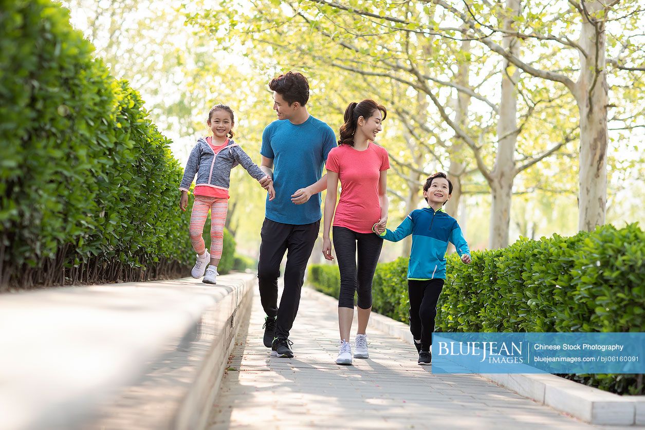Happy young Chinese family playing in park