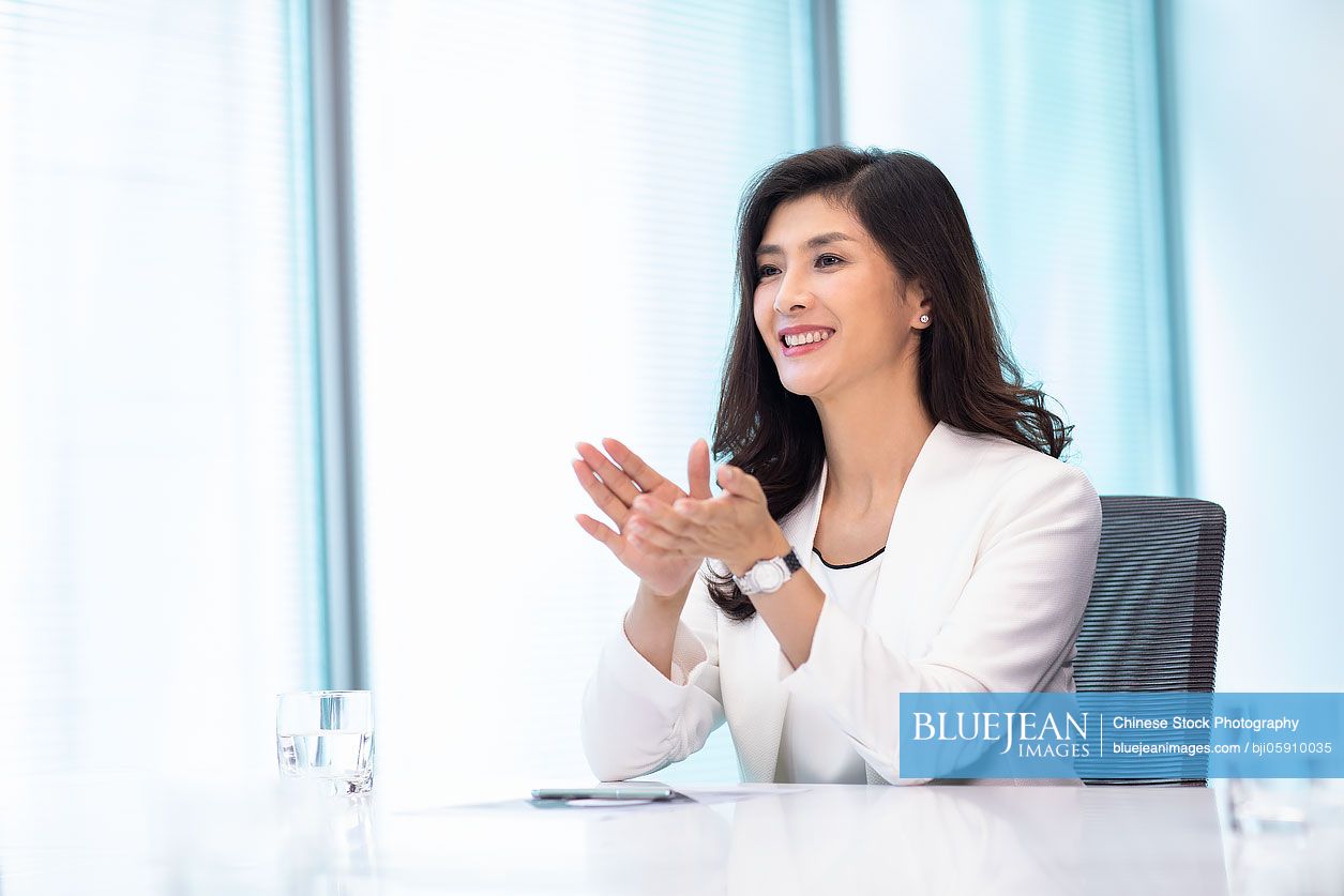 Beautiful Chinese businesswoman applauding in office