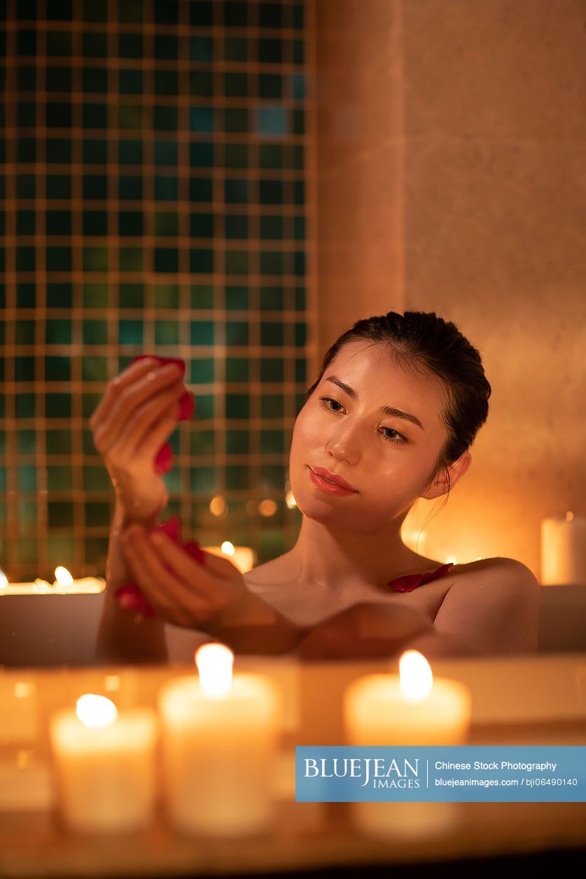 Beautiful young Chinese woman in bathtub with rose petals