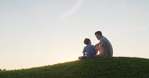 快乐的父子俩坐在草地上