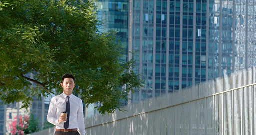 Young Chinese businessman walking with coffee on street,4K