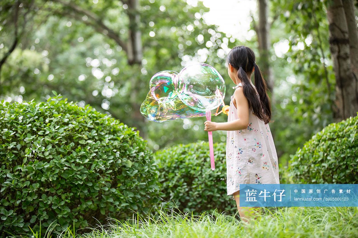 小女孩在草地上吹泡泡