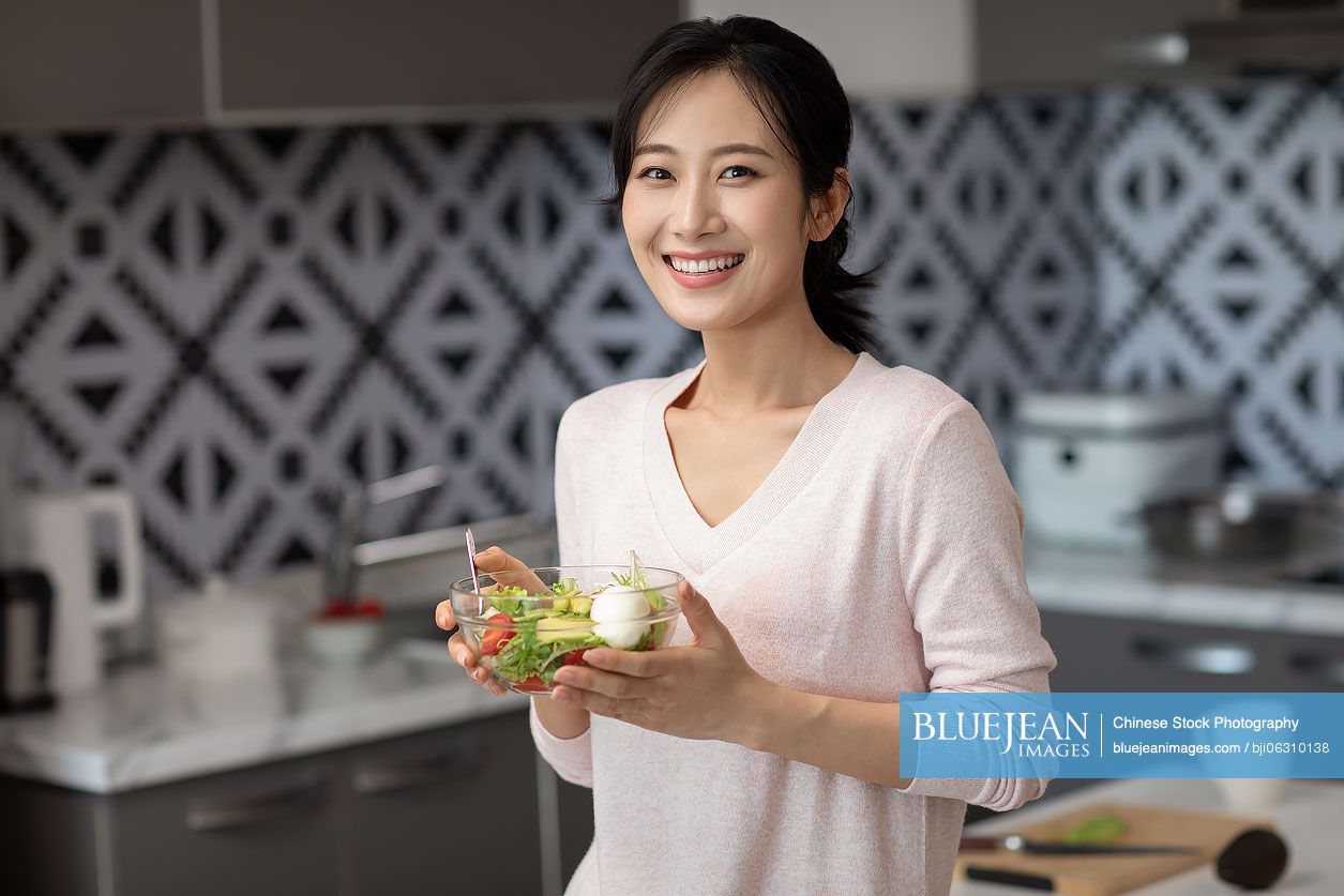 Young Chinese woman cooking in kitchen