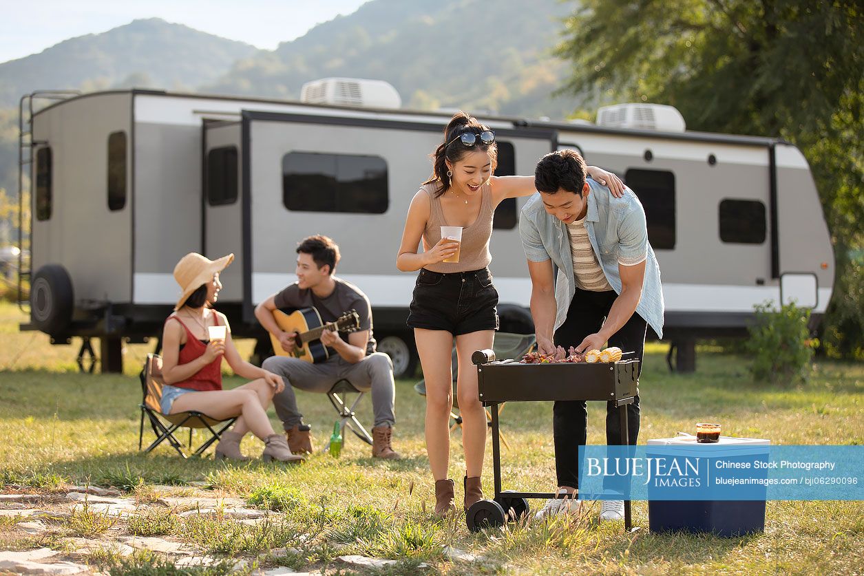 Happy young Chinese friends barbecuing outdoors