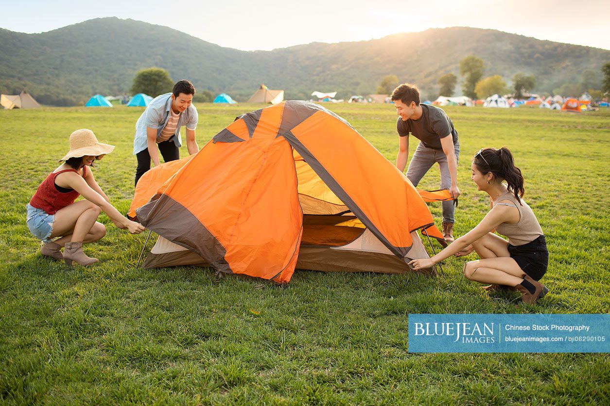 Happy young Chinese friends camping outdoors