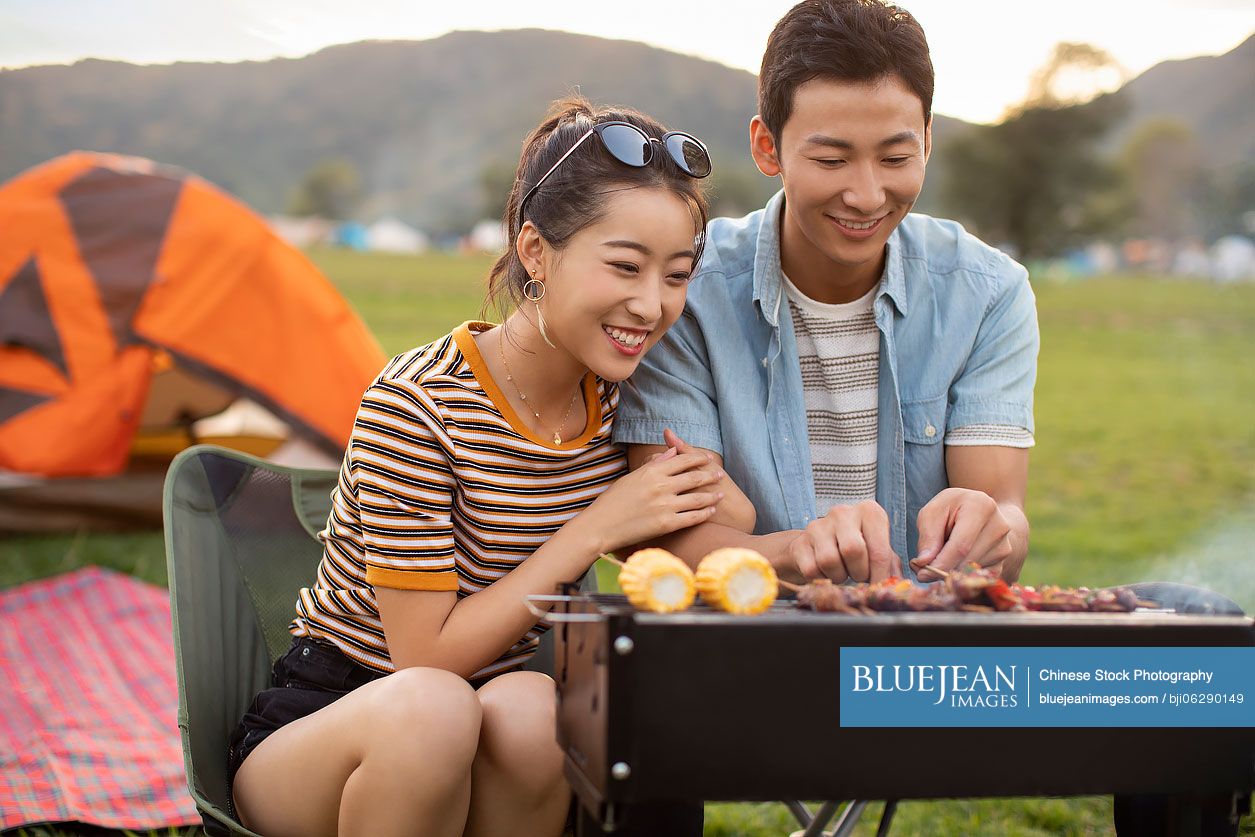 Happy young Chinese couple barbecuing outdoors